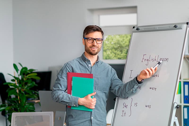 Maestro explicando una lección para aprender inglés rápido en un curso práctico para adultos.