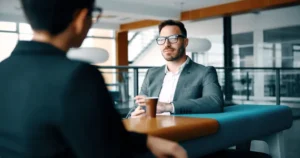 Candidato y reclutador conversando durante una entrevista de trabajo profesional en una oficina moderna.